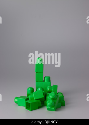 Green and red toy building blocks on grey showing formation. Greenonly framed to the left Stock Photo