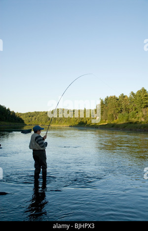 Zachary Colford, 12, plays a fly caught Atlantic salmon on a spey rod on the Miramichi River. Stock Photo
