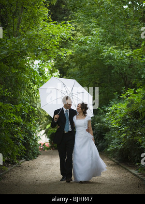 Bride and groom walking in the rain Stock Photo