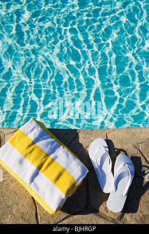 Flip flops and towel by the pool Stock Photo
