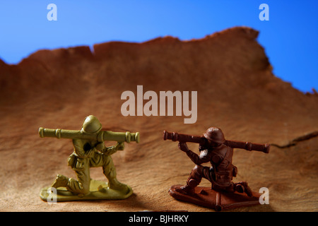 War metaphor, toy little soldiers fighting on wooden mountain Stock Photo