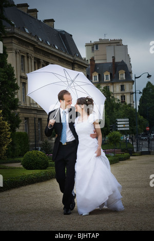 Bride and groom walking in the rain Stock Photo