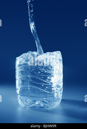 Natural mineral blue water falling down making a plastic bottle shape Stock Photo
