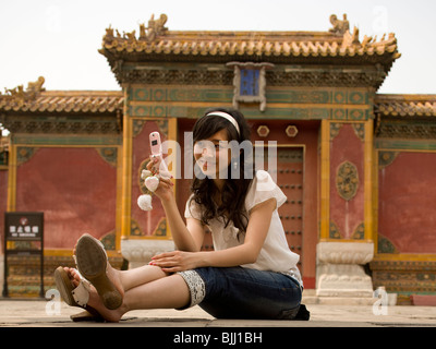 Teenage girl sitting outdoors with cell phone Stock Photo