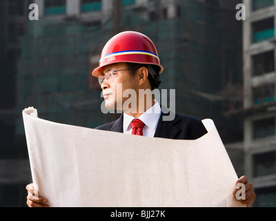 Construction site foreman with blueprints outdoors Stock Photo