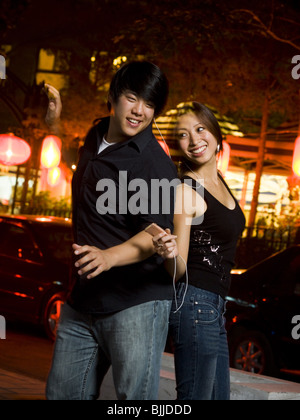 Couple listening to mp3 player outdoors dancing and smiling Stock Photo