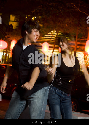 Couple listening to mp3 player outdoors dancing and smiling Stock Photo