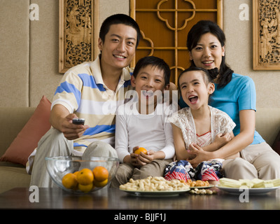 Family on sofa watching television Stock Photo