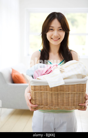 Cheerful young woman holding laundry Stock Photo