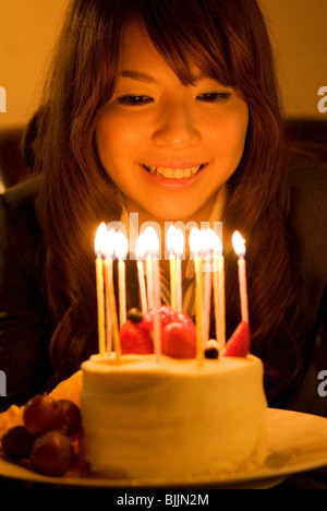 Woman leaning over to blow out the candles on her birthday cake Stock Photo