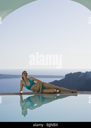 Woman reclining by infinity pool outdoors Stock Photo