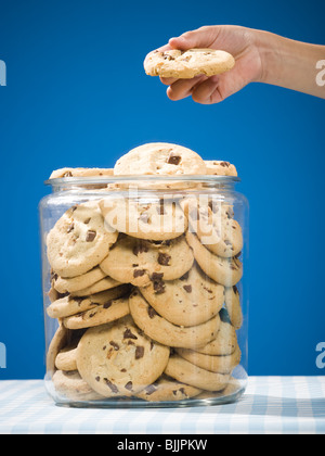 Hand grabbing chocolate chip cookie from jar Stock Photo