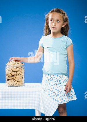 Girl sneaking Chocolate Chip Cookie from cookie jar Stock Photo