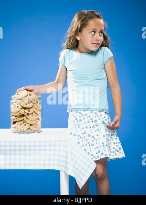 Girl sneaking Chocolate Chip Cookie from cookie jar Stock Photo