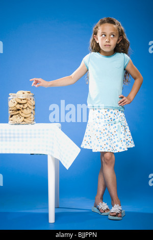 Girl sneaking Chocolate Chip Cookie from cookie jar Stock Photo