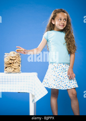 Girl sneaking Chocolate Chip Cookie from cookie jar Stock Photo