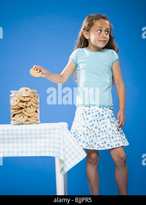 Girl sneaking Chocolate Chip Cookie from cookie jar Stock Photo