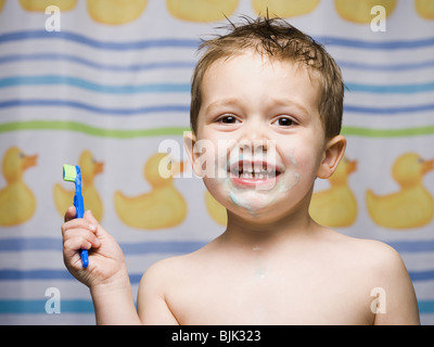 Boy with toothbrush in bathroom smiling Stock Photo