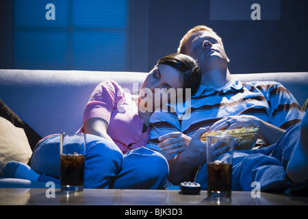 Couple asleep on sofa with bowl of popcorn Stock Photo