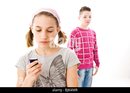 Boy standing behind a girl who is listening to music with headphones Stock Photo