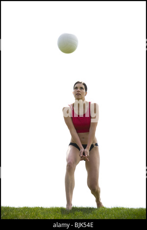 Woman in bikini playing volleyball outdoors on grass Stock Photo