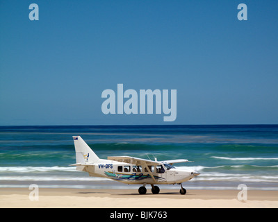 A light aircraft lands on the 75 Mile Beach sand highway on Fraser Island, Australia Stock Photo