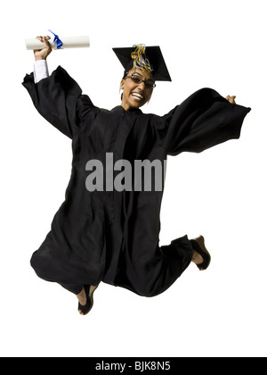 Woman in graduation gown and Blank Sign with diploma jumping Stock Photo