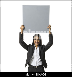 Businesswoman standing with blank sign over head Stock Photo