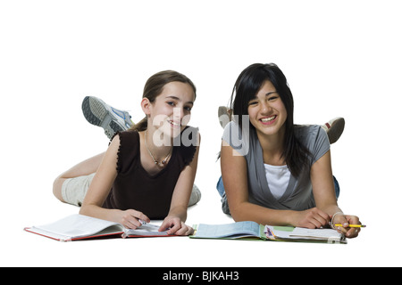 Two girls lying down doing homework Stock Photo