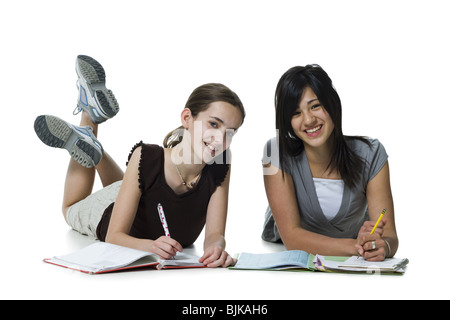 Two girls lying down doing homework Stock Photo