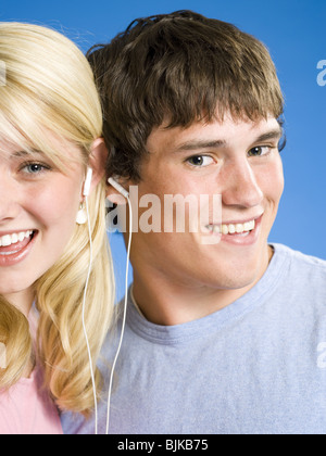 Portrait of a young couple with ear buds smiling Stock Photo