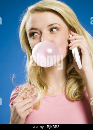 Girl talking on cell phone and blowing bubble Stock Photo