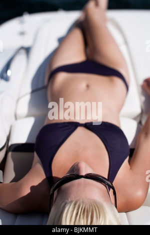 Woman in bikini sunbathing on boat Stock Photo