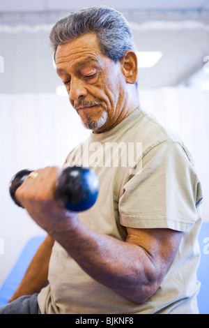 Man with one leg sitting and exercising with weights Stock Photo