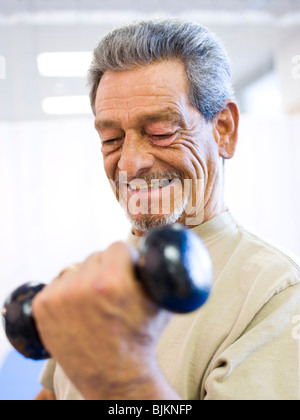 Man with one leg sitting and exercising with weights Stock Photo