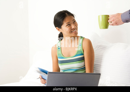 Woman working from bed Stock Photo
