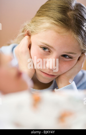 Young girl sitting by brother in hospital bed Stock Photo