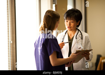 Female doctor explaining patient records to nurse Stock Photo