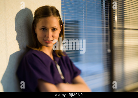 Nurse leaning on wall with arms crossed Stock Photo