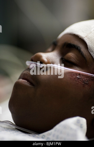 Boy in hospital bed with head bandages with father by his side Stock Photo