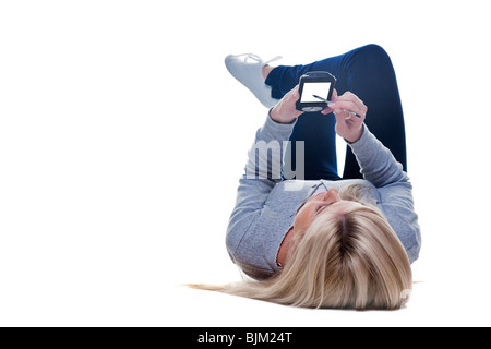 Woman lying down writing on her pda isolated on a white background, space on the screen for your own message. Stock Photo