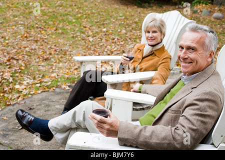 Mature couple in wooden chairs toasting Stock Photo