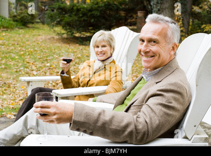 Mature couple in wooden chairs toasting Stock Photo