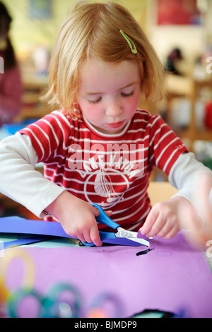 Red-haired girl doing craft in a kindergarten Stock Photo