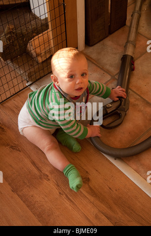 Baby boy (11 months old) playing with a vacuum cleaner, Hampshire, England. Stock Photo