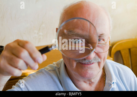 Pensioner looking through a magnifying glass Stock Photo