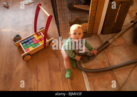 Baby boy (11 months old) playing with a vacuum cleaner, Hampshire, England. Stock Photo