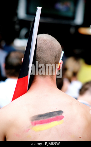 German soccer fan during the World Cup with a cigarette behind his ear, German flag painted on his back Stock Photo