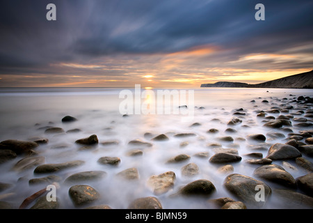 Sun setting over rocks on the shore at Compton Bay. Isle of Wight, England, UK Stock Photo