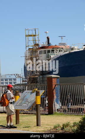 Tourist reading a map during a walking tour of ship painting and maintenance area around the V&A Waterfront Cape Town S Africa Stock Photo